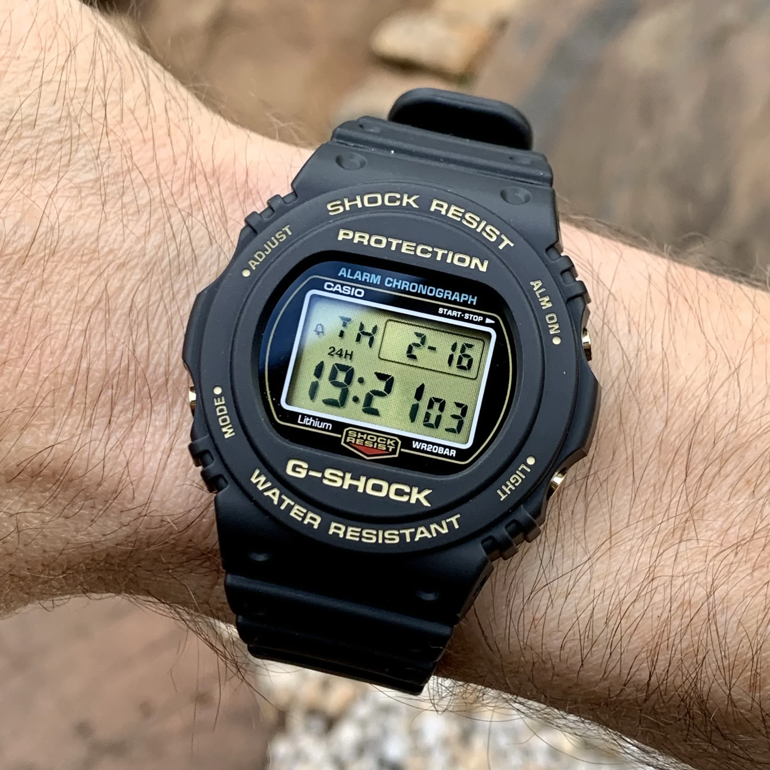 Reloj digital Casio G-Shock DW-5735D-1BDR edición 35 aniversario con bisel negro, letras doradas y pantalla LCD dorada en la muñeca