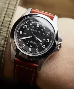 Hamilton Khaki Field King Auto H64455533 en la muñeca, con esfera negra y correa de cuero marrón
