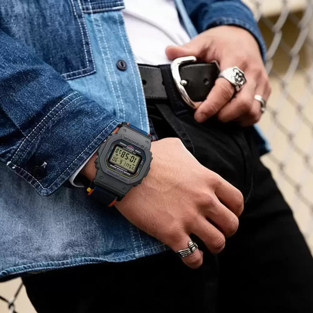 Reloj G-SHOCK DW-5600MNC-8A2 con caja gris, correa textil azul y naranja y cierre magnético