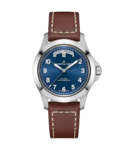 Hamilton Khaki Field King Day-Date H64475540 visto en la muñeca, con caja de acero de 40 mm, esfera azul, indicador de día y fecha y correa de cuero marrón.