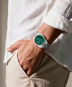 Reloj verde de acero Movado en muñeca con camisa blanca