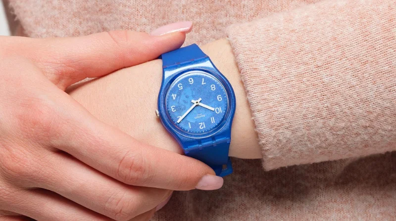 Swatch Blurry Blue GL124 en la muñeca Swatch Blurry Blue GL124 en la muñeca de una mujer con suéter rosa claro
