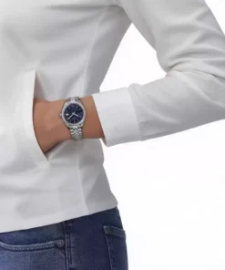Mujer luciendo un Tissot Ballade de esfera azul con camisa blanca y jean
