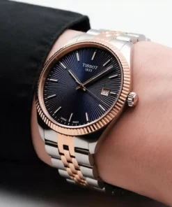 Tissot Ballade para hombre con esfera azul, bisel color oro rosa y malla de acero bicolor.