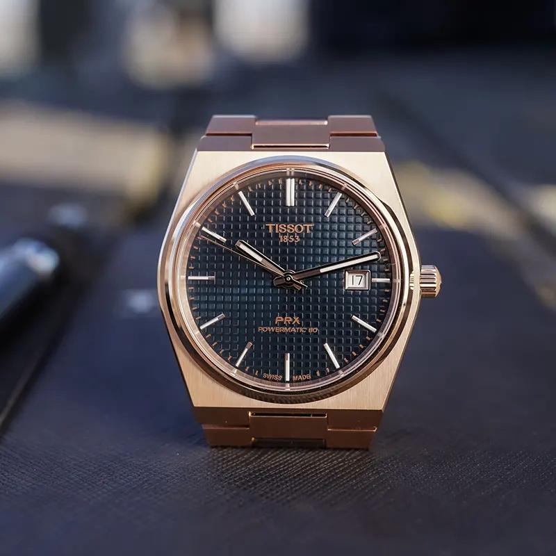 Vista frontal del Tissot PRX Powermatic 80 con esfera azul, índices aplicados y acabado color oro rosa
