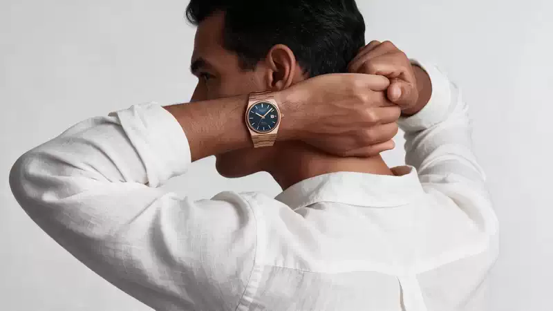 Vista lateral de un hombre con camisa blanca usando el Tissot PRX Powermatic 80 de 40 mm