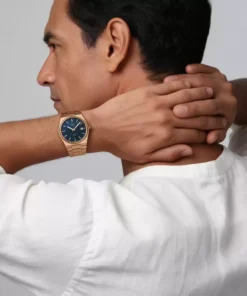 Hombre con camisa blanca llevando el Tissot PRX color oro rosa y esfera azul en la muñeca